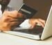 A customer using a laptop and credit card to securely order a Coway water purifier online.