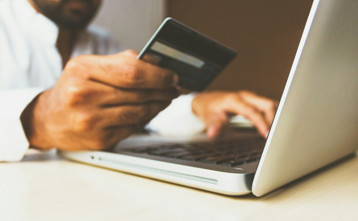 A customer using a laptop and credit card to securely order a Coway water purifier online.