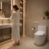 Modern premium bathroom interior featuring the slim white Coway BAS-42B bidet with a blue nightlight, installed on a minimalist toilet as a woman prepares for her daily routine.